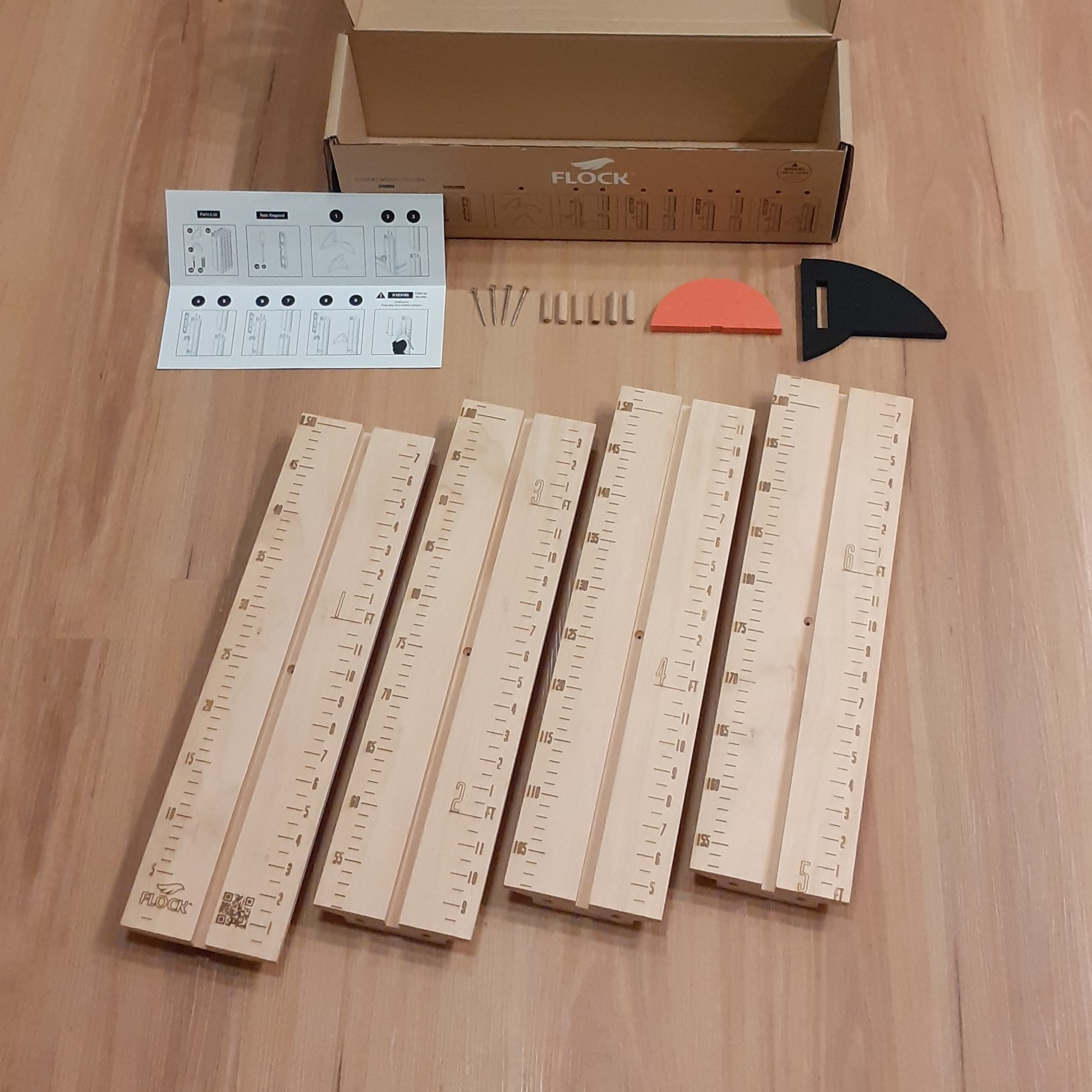 An opened box containing all parts that come with a FLOCK height chart